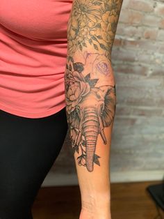 a woman's arm with an elephant and flowers tattoo on the left side of her arm