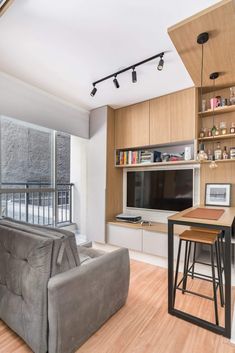 a living room filled with furniture and a flat screen tv mounted to a wall next to a window