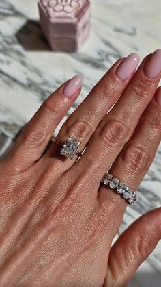 a woman's hand with two engagement rings on her left and the other half of her finger