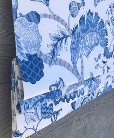 a blue and white floral print roman blind with matching roller shades on the outside of it