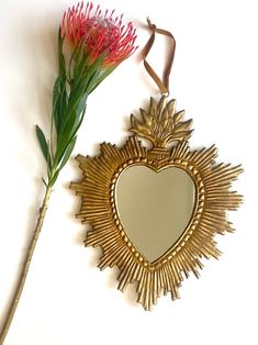 Mirror Sacred Heart Ex Voto - A Divine Religious Ornament Elevate your spiritual space with our exquisite Mirror Sacred Heart Ex Voto, a testament to both faith and artistry. This beautiful piece features a burning heart design crafted from gilded metal, making it a symbol of deep devotion and elegance. Key Features: Divine Symbolism: The burning heart design symbolizes the sacred heart, a powerful and beloved symbol of faith and love. Gilded Metal: Crafted from gilded metal, this mirror radiates a warm, golden glow, adding a touch of opulence to your spiritual decor. Wall-Mounted: The mirror is equipped with a sturdy metal clip on the back for easy wall mounting, allowing you to display it in your sacred space with grace. Dimensions: Height: 25 cm (approximately 9.84 inches) Width: 20 cm Sacred Heart Ornament, Sacred Heart Home Decor, Sacred Heart Lamp, Vintage Heart Mirror, Mexican Milagros Sacred Heart, Spiritual Space, Burning Heart, Religious Ornaments, Prayer Corner