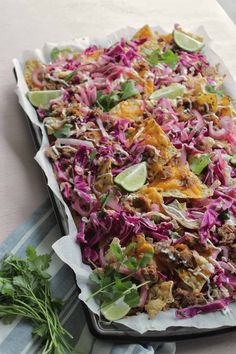 a tray filled with coleslaw and meat on top of a striped table cloth