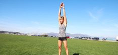 a woman standing on top of a lush green field holding up a frisbee