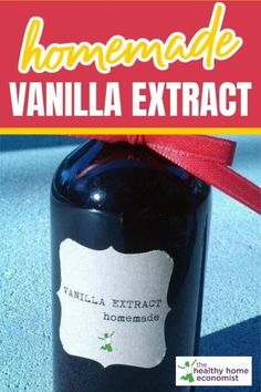 a bottle of homemade vanilla extrait sitting on top of a blue surface with a red ribbon around it