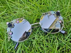 💖Women's pretty statement sunglasses. 💖These round embellished glasses are the perfect feminine touch to add to your spring / summer outfits. 💖The frames are silver metal and they have silver mirrored lenses. On either side of the glasses they have a mixture of bronze ornate details, black roses, sequin flowers and irredecent rhinestones. 💖A great accessory for holidays, music festivals or everyday wear.  💖UV protection 💖Exclusive design made by myself that you won't see anywhere else. 💖All glasses come in a black to keep them safe for delivery but please also handle with care as they are handmade. Just think of them as wearing tiny bits of wearable art.  💖Checkout the full collection of Sunglasses here :  https://www.etsy.com/uk/shop/AlexisExclusive?ref=s2-header-shopname (Colours Holidays Music, Winter Knit Headband, Sequin Flowers, Statement Sunglasses, Black Jewel, Black Roses, Funky Outfits, Rave Festival, Music Festivals