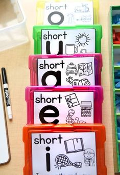 three plastic containers filled with different types of short and long words on a table next to some pens