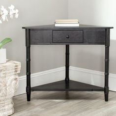 a small wooden table with a drawer on the top and a plant in front of it