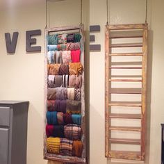 an old ladder hanging from the wall next to a rack with scarves on it