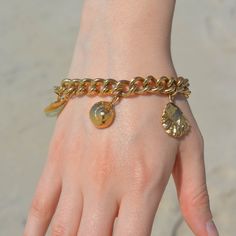 Created with an array of seashells, this is the ultimate beachcombers bracelet. Take a piece of the ocean with you wherever you go and be reminded of nature. We love chunky gold jewelry and this one is a favorite. Gold Filled Curb chain + Extender 6 Charms Gold Metal Charm Bracelet For Beach, Gold Shell Bracelets For Gift, Gold Shell Bracelets For Gifts, Gold Chain Bracelets For Beach, Bohemian Gold Chain Bracelet With Lobster Clasp, Unique Gold Bracelets With Charms, Ocean-inspired Gold Shell Bracelets, Unique Gold Charm Bracelet, Gold Bracelets With Charms