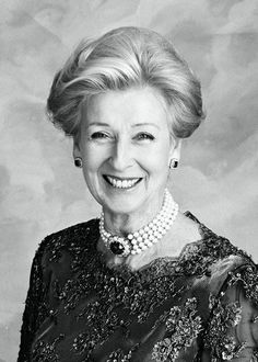 an old black and white photo of a woman in a dress smiling for the camera