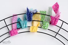 several pieces of fabric are placed on a wire rack with hair clips attached to them