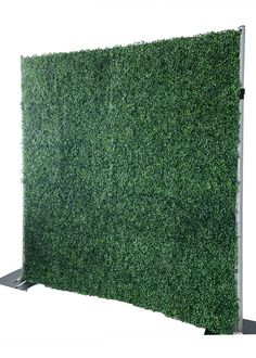 a green wall covered in grass on top of a metal stand with a white background