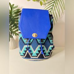 a blue purse sitting on top of a white table next to a potted plant