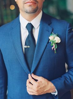 a man in a blue suit with a boutonniere on his lapel