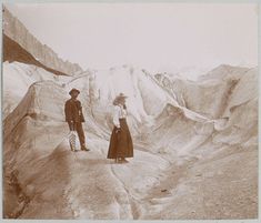 an old photo of two people standing on top of a mountain