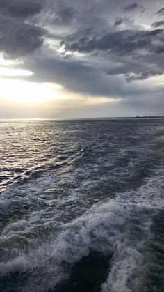 the wake of a boat in the ocean under a cloudy sky