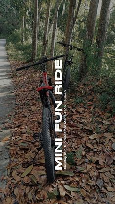 a bicycle parked on the side of a leaf covered road with trees in the background