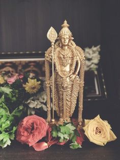 a golden statue sitting on top of a table next to flowers