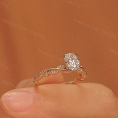 a woman's hand holding an engagement ring with a diamond in the middle and a wedding band on top