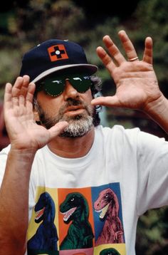 a man wearing sunglasses and a t - shirt with dinosaurs on it