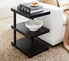 a white bowl sitting on top of a black table next to a couch and coffee table