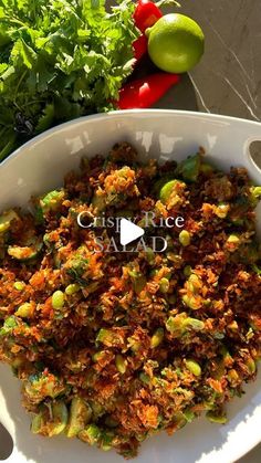 a white bowl filled with food next to some veggies and lime wedges