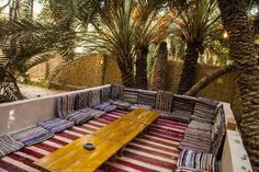 an outdoor seating area with striped cushions and palm trees