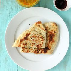 two quesadillas on a white plate next to some dipping sauce