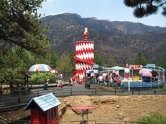 an amusement park in the mountains with people riding on rides and other things around it