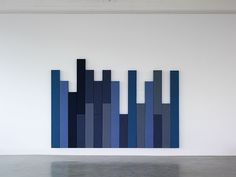 an abstract piece of art is displayed in a white room with blue and gray stripes