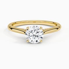 a yellow gold engagement ring with a round cut diamond in the center, on a white background