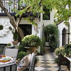 an outdoor dining area with black and white checkered tile flooring, potted trees, and patio furniture