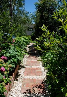 a brick path surrounded by trees and flowers