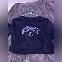 This Is A Navy Blue Crop Top That Says Beach On It And Big Letters, And It Is In Great Condition. Never Worn. Casual Beach Crop Top With Crew Neck, Casual Beach Season Crop Top For Vacation, Casual Short Sleeve Crop Top For Beach, Casual Crew Neck Crop Top For Beach, Casual Short Sleeve Crop Top For Beach Season, Casual Crew Neck Crop Top For Vacation, Blue Short Sleeve Crop Top For Beach, Blue Short Sleeve Crop Top For The Beach, Blue Trendy Tops For Beach Party