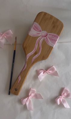 a wooden cutting board with pink ribbon bows and a pencil on the table next to it