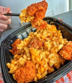 a person holding a spoon full of macaroni and cheese with fried chicken on top