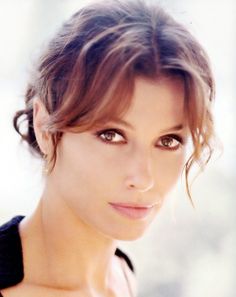 a close up of a woman with short hair and brown eyes wearing a black dress