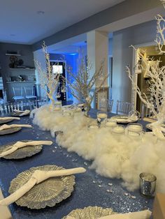 a table set up for a formal event with white and silver decorations on top of it