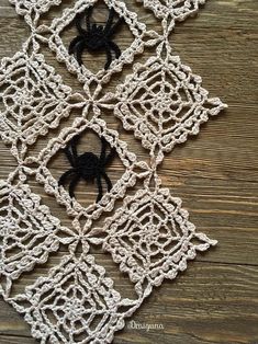 a crocheted doily with a black spider in the center on a wooden surface