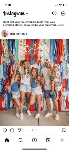 a group of people standing next to each other in front of a wall with clothes on it