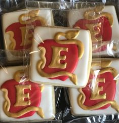 four decorated cookies sitting on top of each other in plastic wrappers with red and gold letters