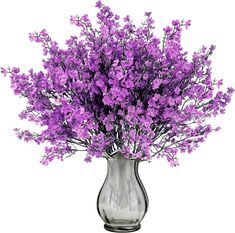 a glass vase filled with purple flowers on a white background