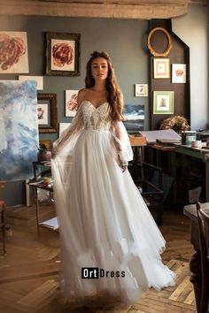 a woman in a white wedding dress standing on a wooden floor with her arms behind her back