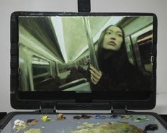 a woman is looking out the window on a train with her head in the mirror