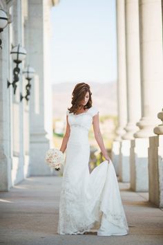 a woman in a wedding dress is walking down the street with her bouquet on her hand