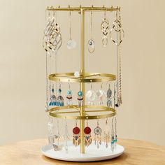 a gold jewelry holder on top of a wooden table with lots of earrings hanging from it