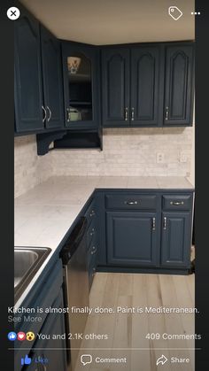 an empty kitchen with blue cabinets and white counter tops in the middle of the room