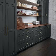 a kitchen with gray cabinets and wooden counter tops