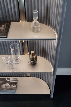 two glass shelves with books and glasses on them