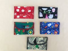 four small wallets are lined up on a white surface, each with different designs